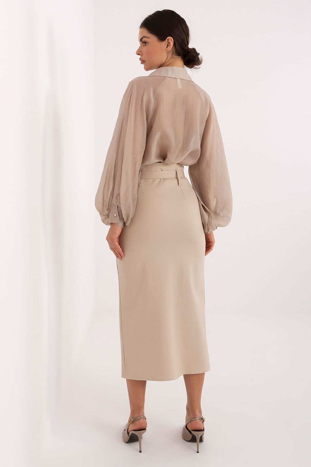 Woman wearing a beige blouse and skirt set on a white background