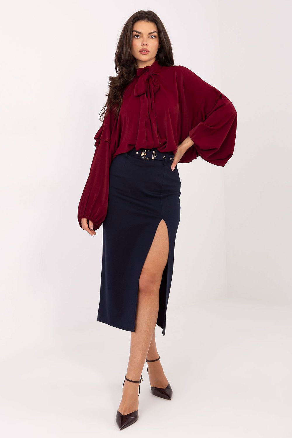 Woman wearing a burgundy blouse and navy skirt on a white background