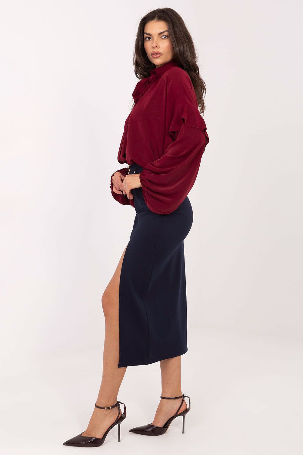 Woman wearing a burgundy sweater and navy skirt on a white background