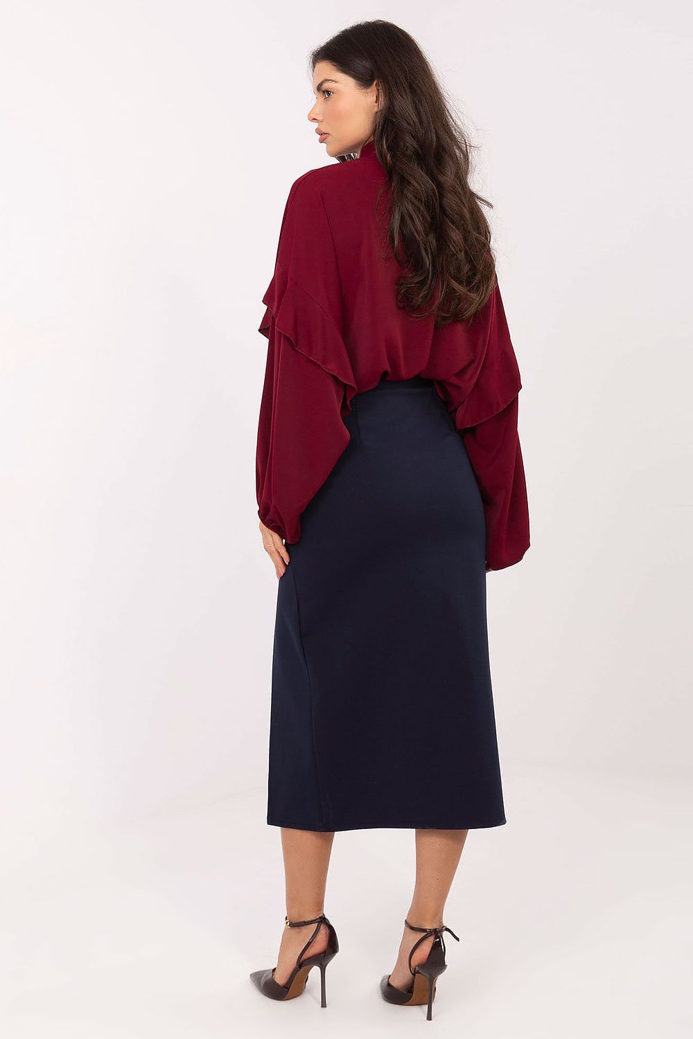 Woman wearing a burgundy top and navy skirt on a white background