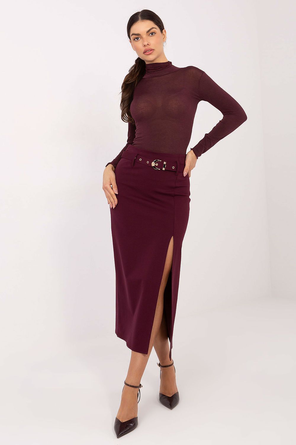 Woman wearing a burgundy long-sleeve top and skirt with a belt on a white background