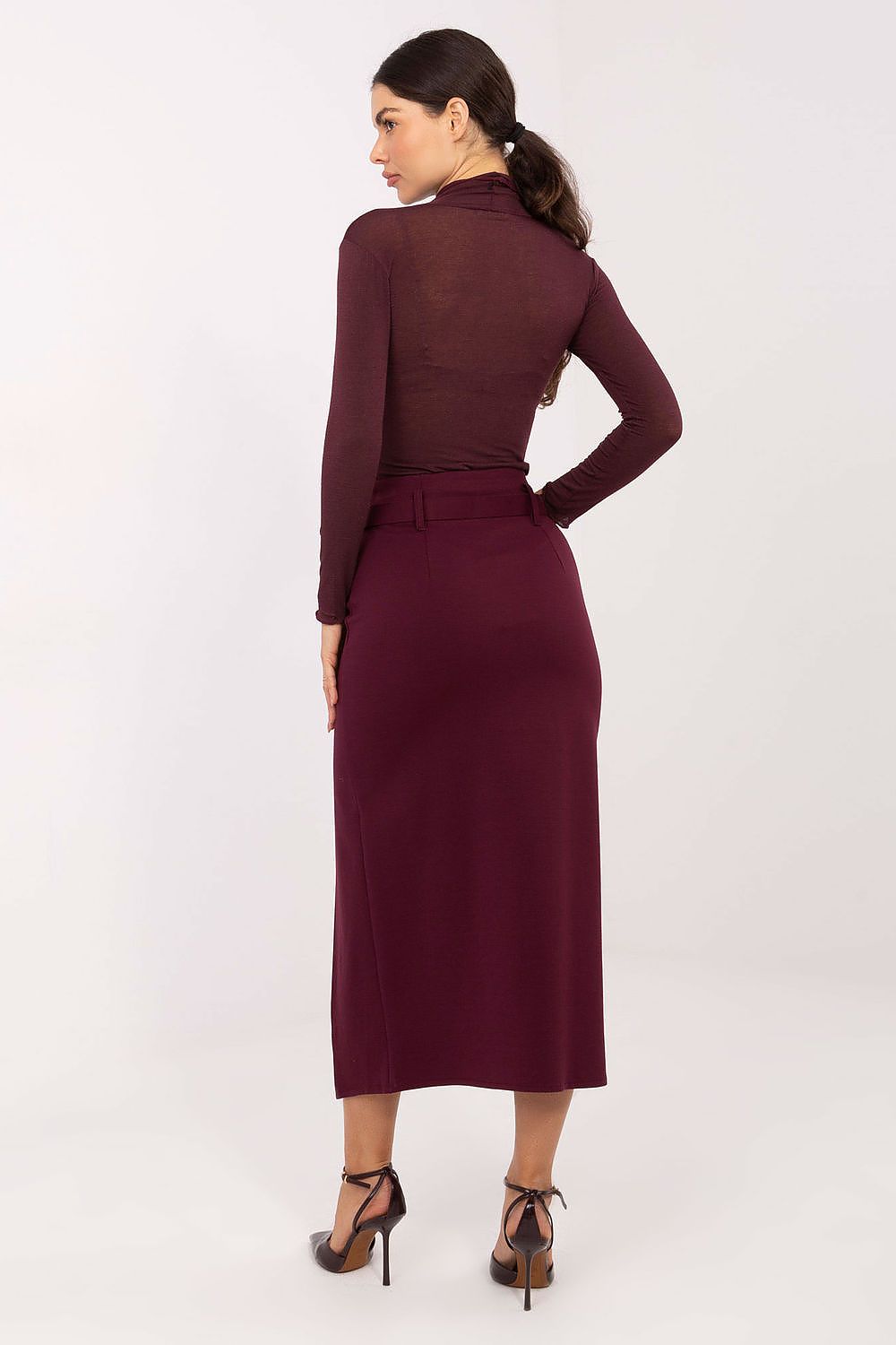 Woman wearing a burgundy dress with long sleeves on a white background