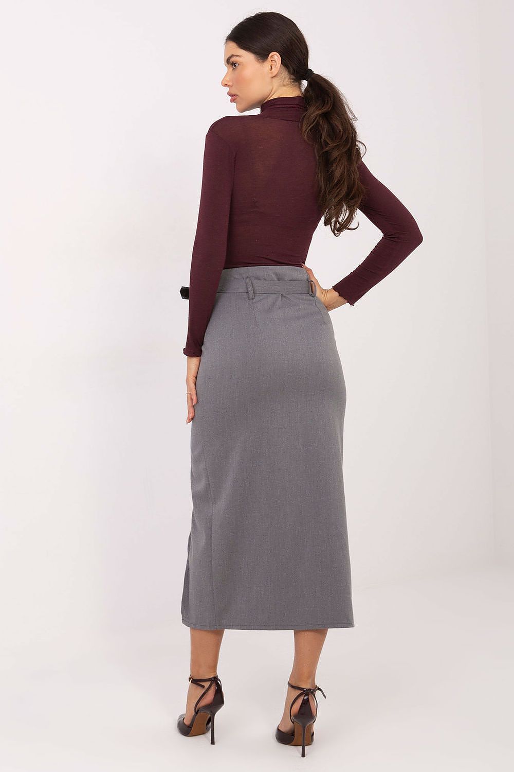 Woman wearing a burgundy top and gray skirt on a white background