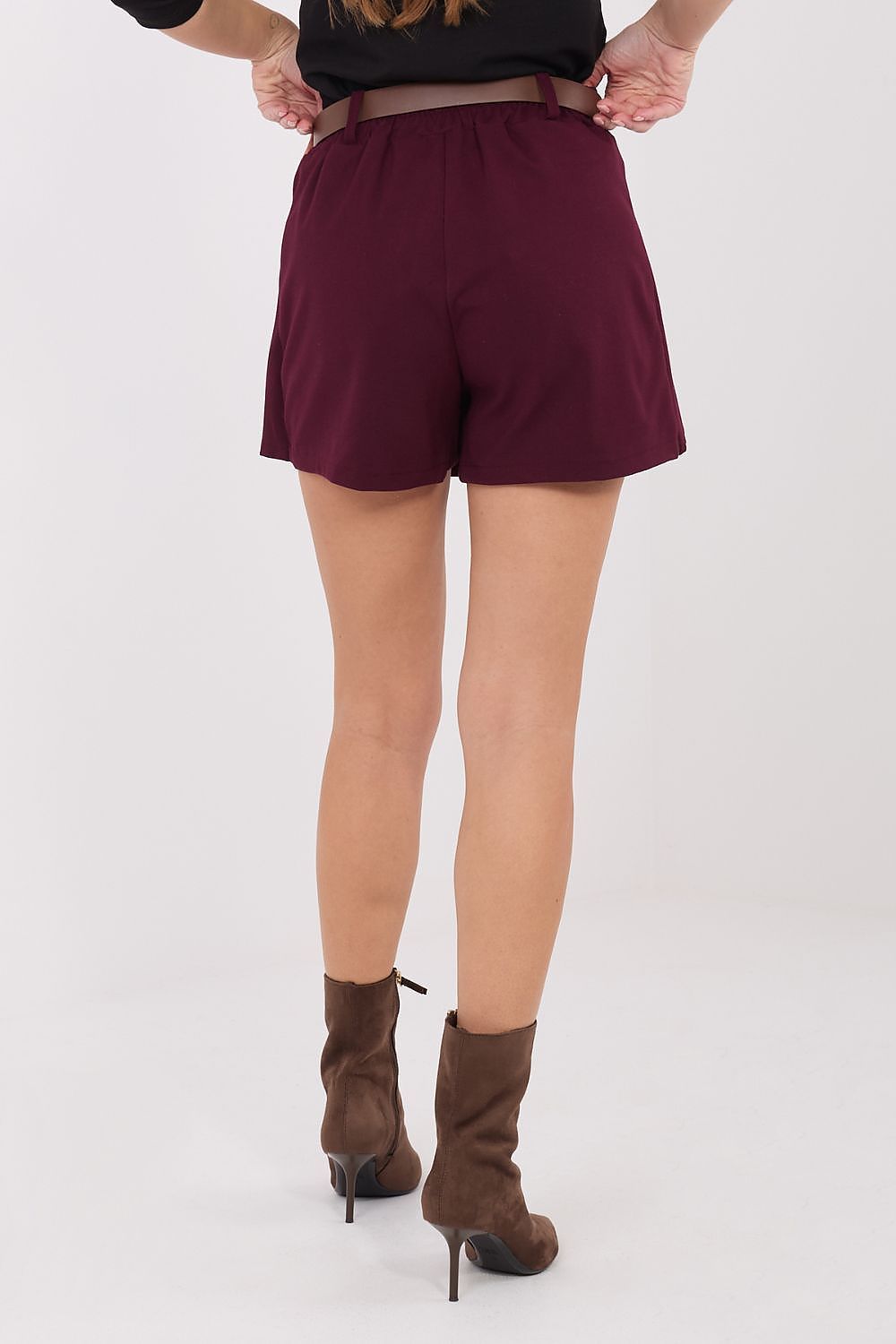 Person wearing maroon shorts and brown high-heeled boots on a white background