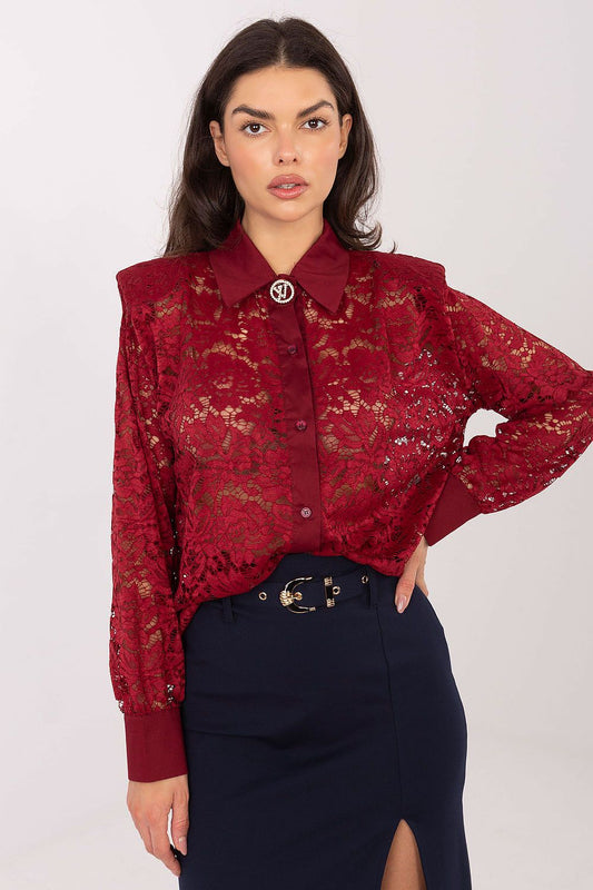 Woman wearing a red lace blouse with a plain background