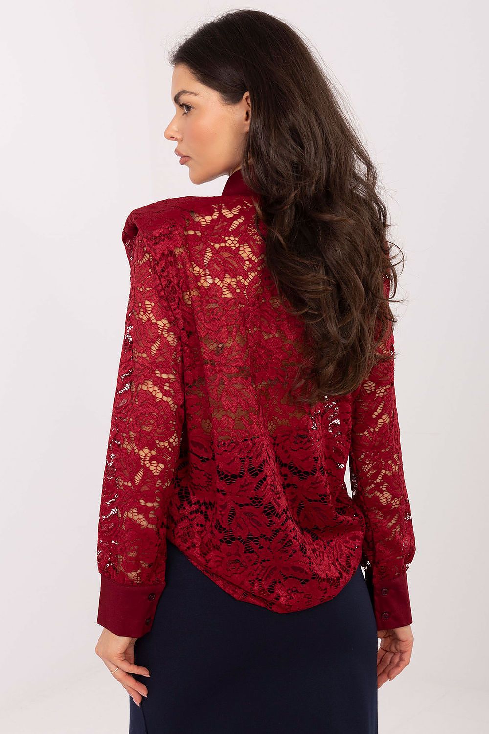 Woman wearing a red lace blouse against a white background
