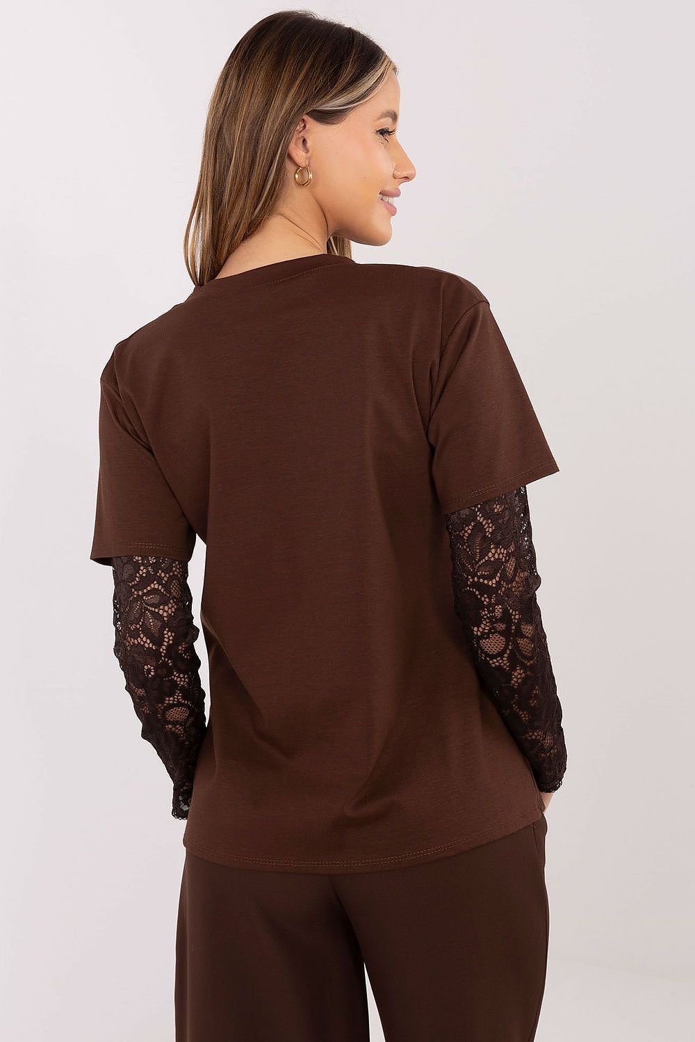 Woman wearing a brown outfit with lace sleeves on a white background