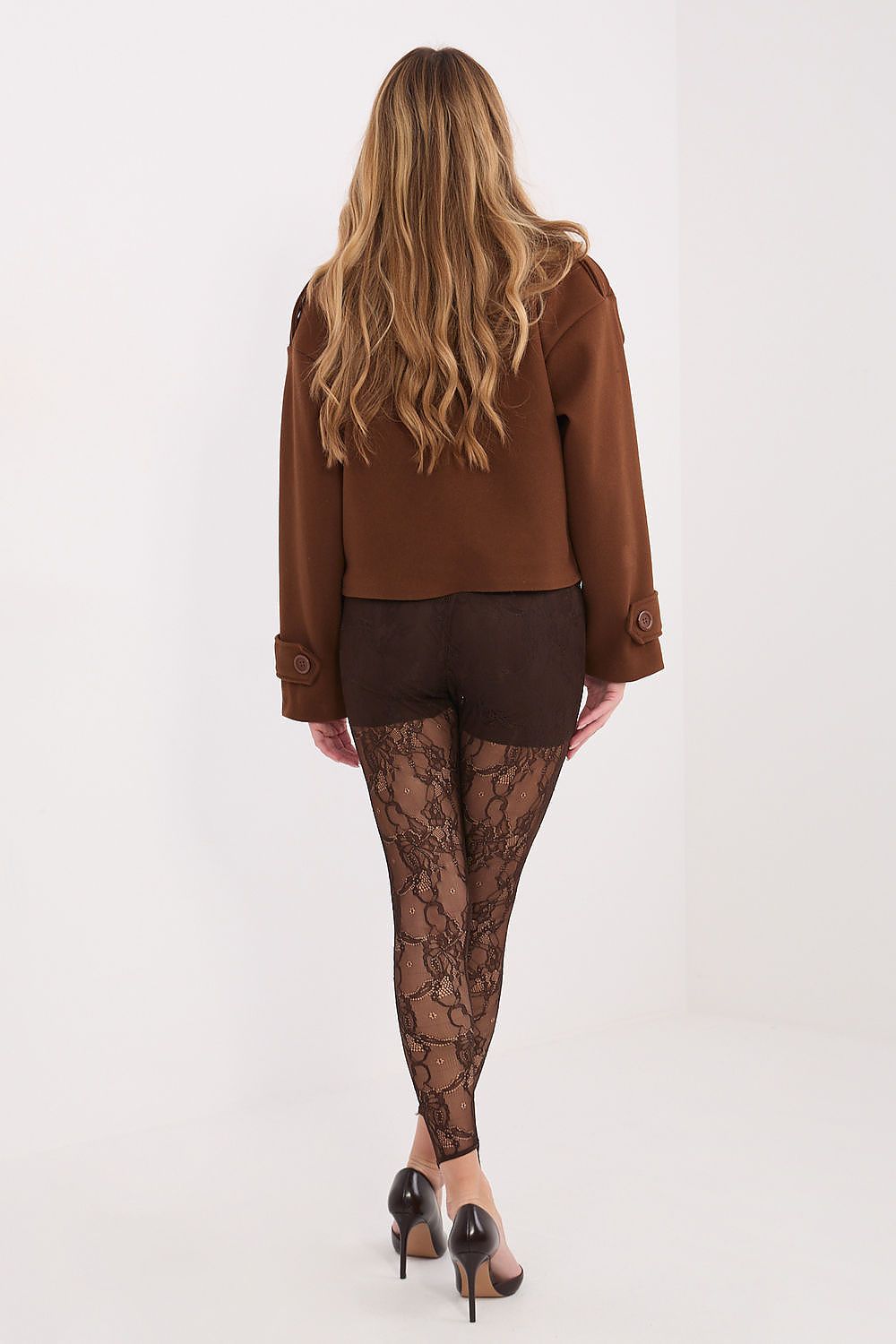 Person wearing a brown outfit with lace leggings on a white background
