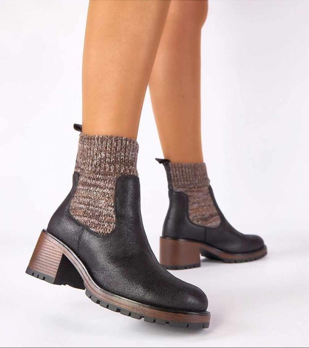 Black ankle boots worn with patterned socks on a white background