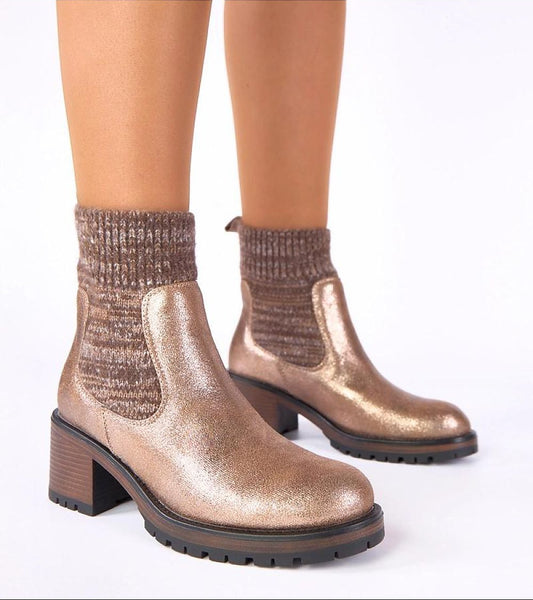 Bronze metallic ankle boots worn with brown textured socks on a white background