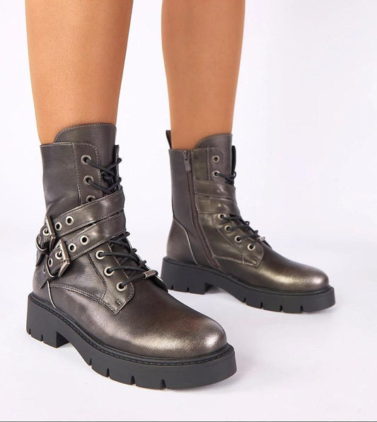 Bronze combat boots worn by a person on a white background