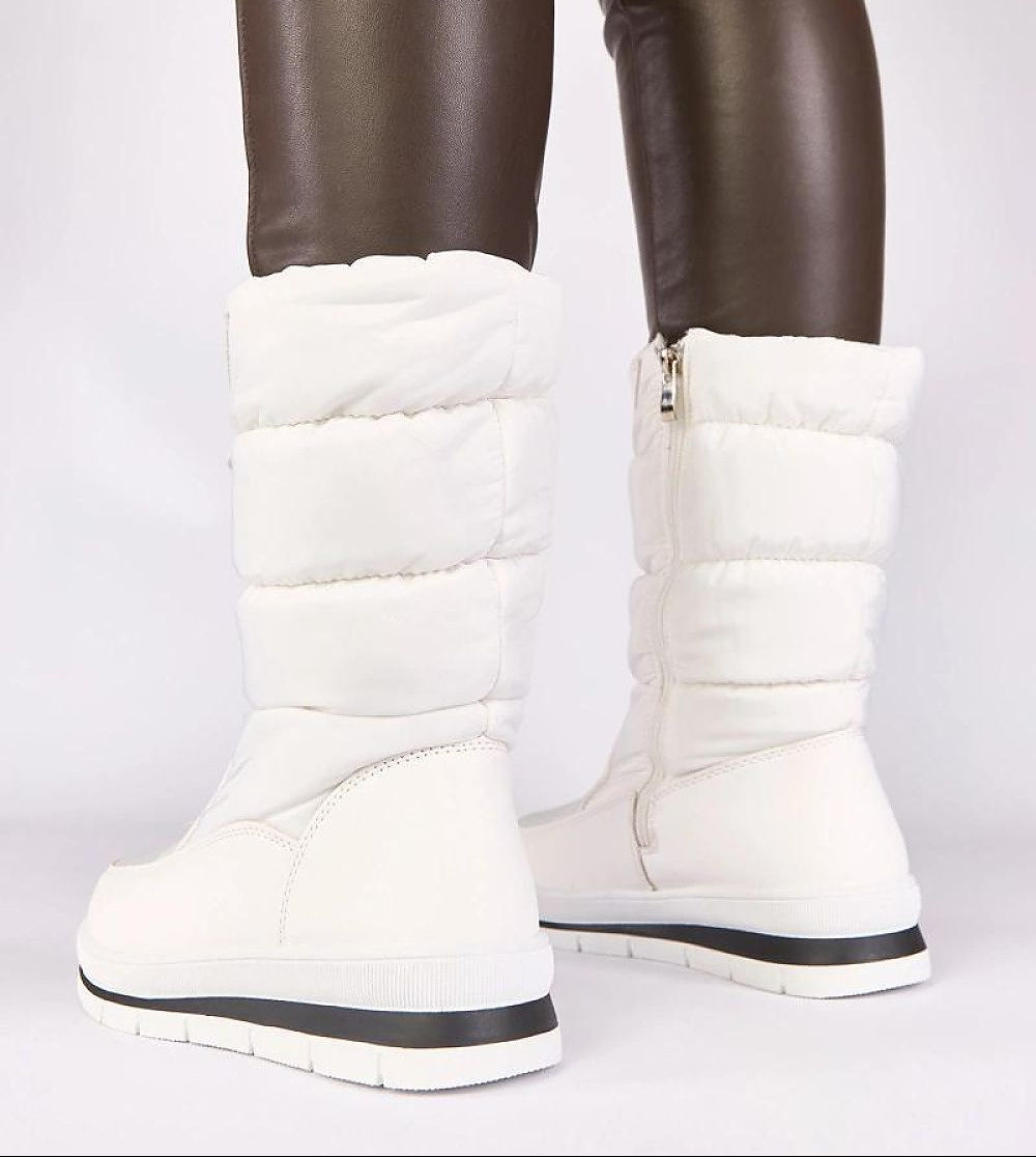 White winter boots worn with brown pants on a white background