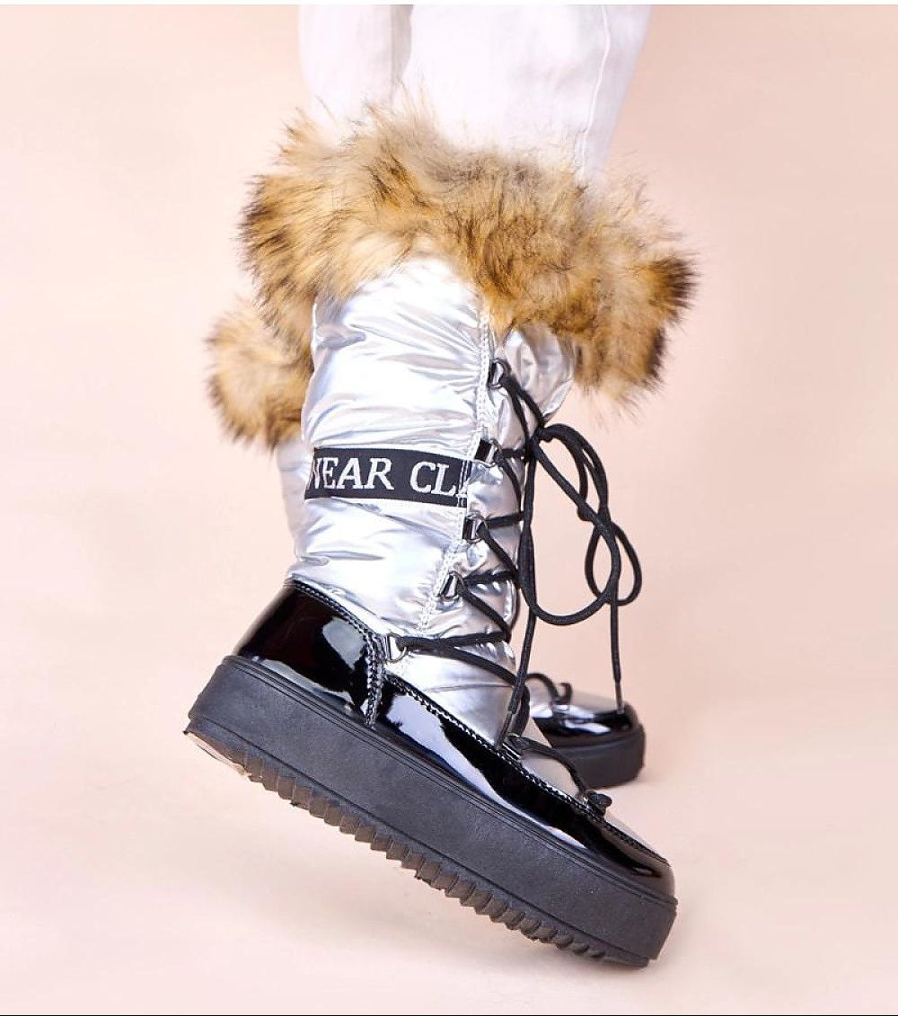 Silver metallic boot with fur trim and 'Bear Club' branding on a beige background