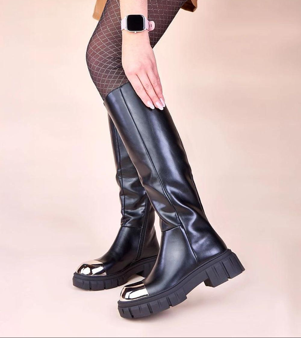 Black knee-high boots worn with a neutral background