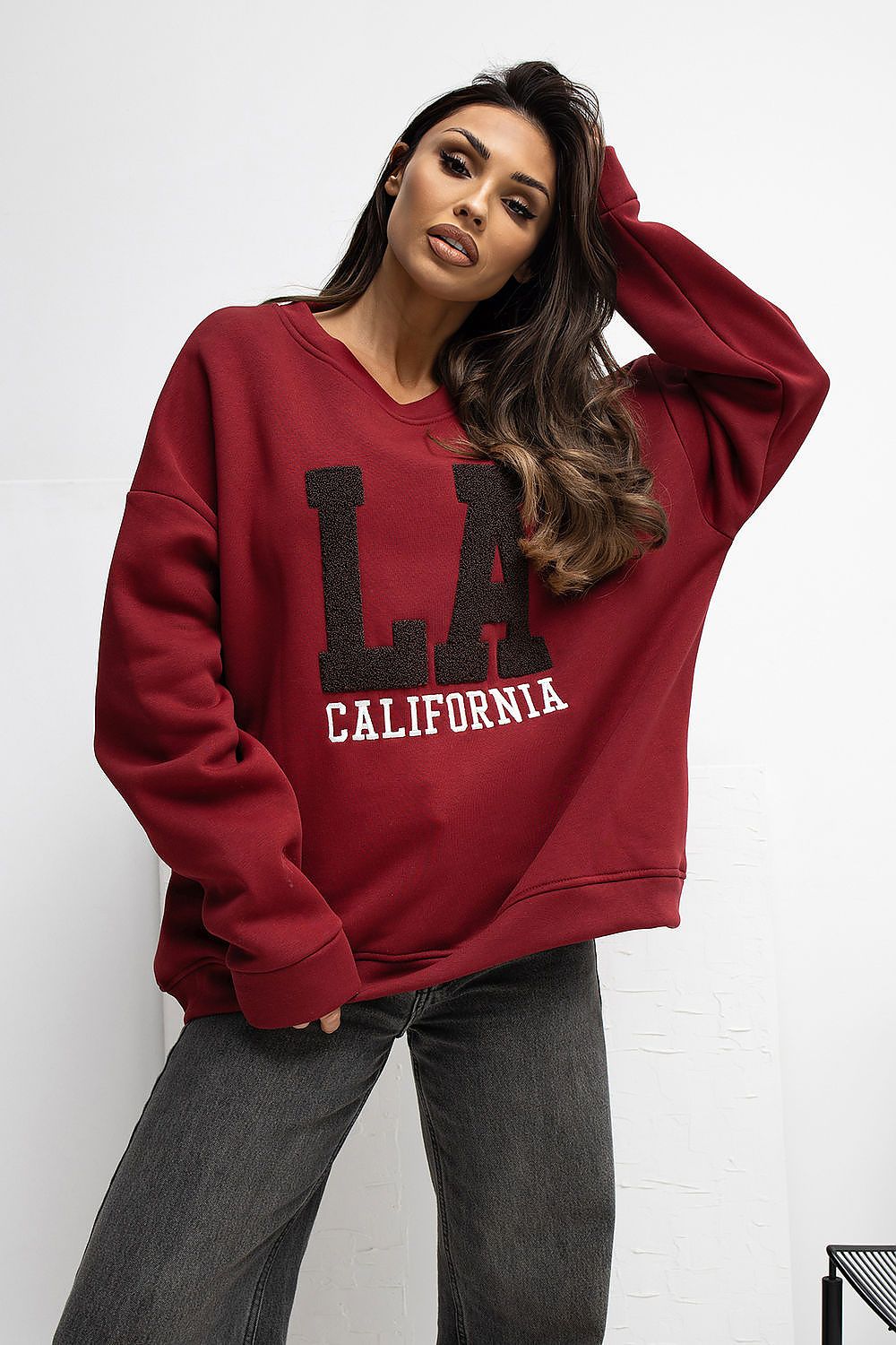 Woman wearing a red 'LA California' sweatshirt against a white background