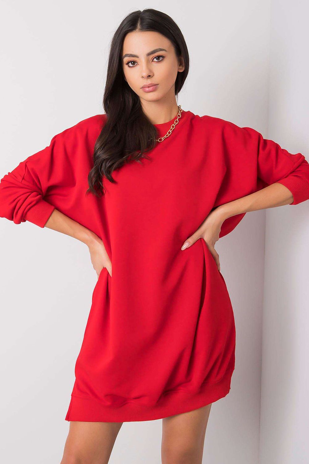 Woman wearing a red sweatshirt dress against a white background
