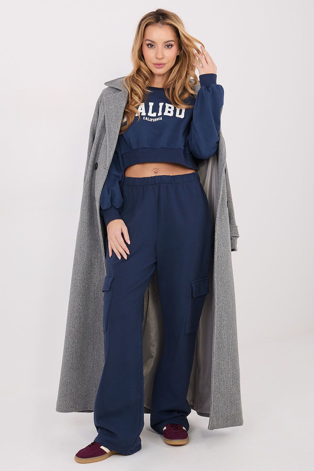 Woman wearing a navy tracksuit with 'ALIBU' branding, standing against a white background.