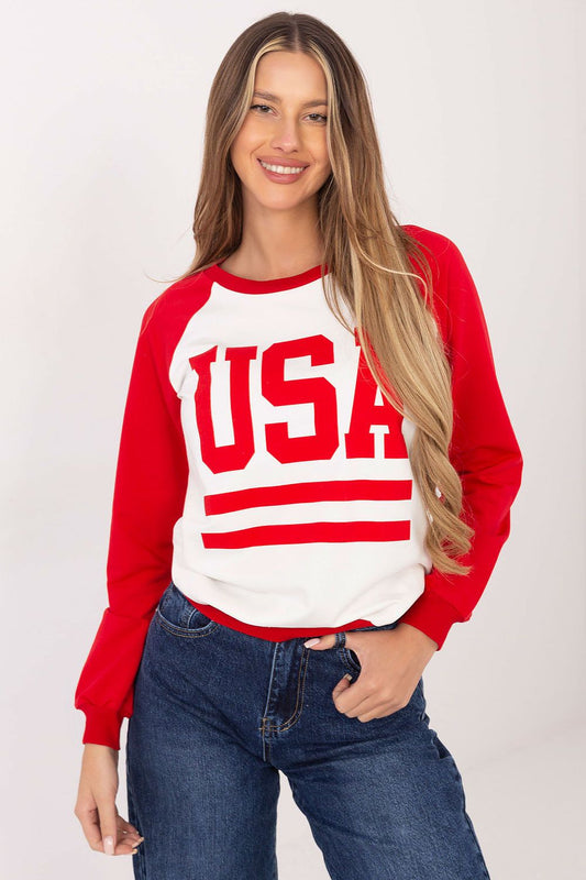 Woman wearing a red and white 'USA' sweater with blue jeans on a plain background