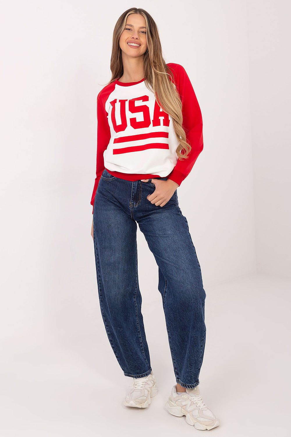 Woman wearing a red and white 'USA' sweater with blue jeans on a white background