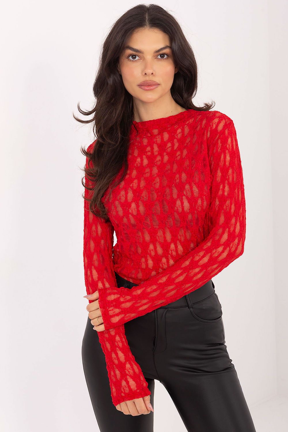 Woman wearing a red sheer top with black pants on a white background