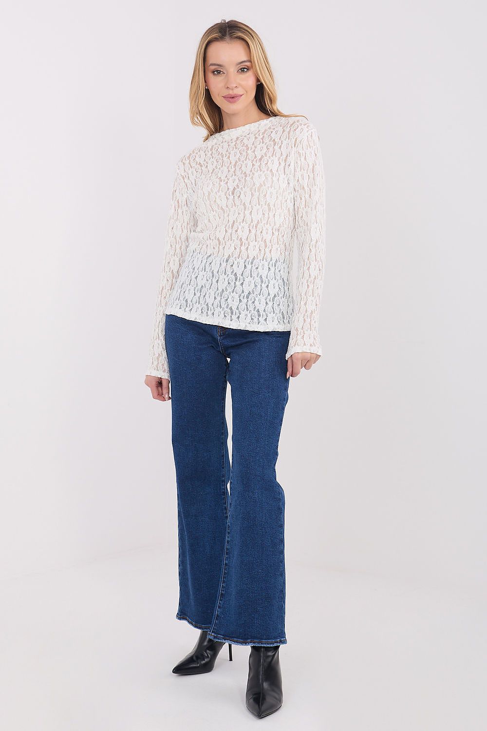 Woman wearing a white textured top and blue jeans on a white background