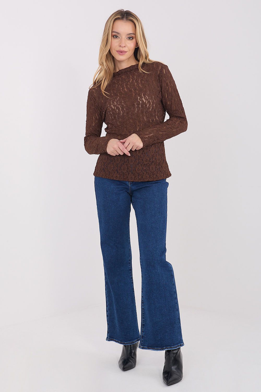 Woman wearing a brown sweater and blue jeans on a white background