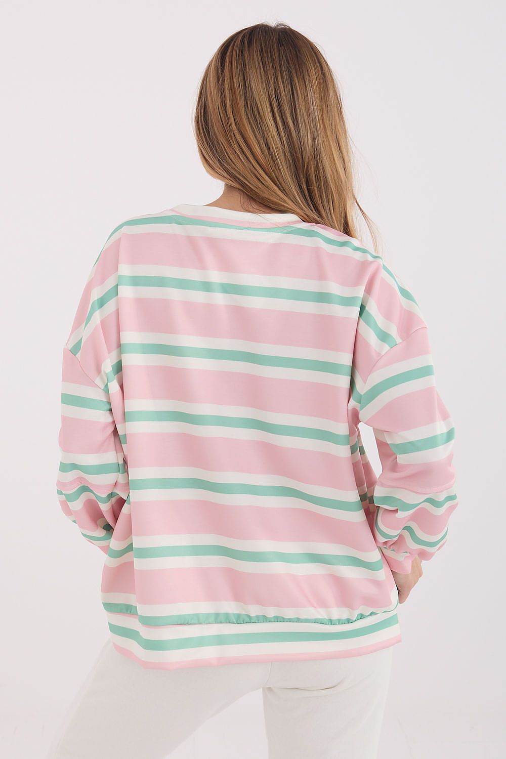 Person wearing a pink and green striped long-sleeve shirt on a white background