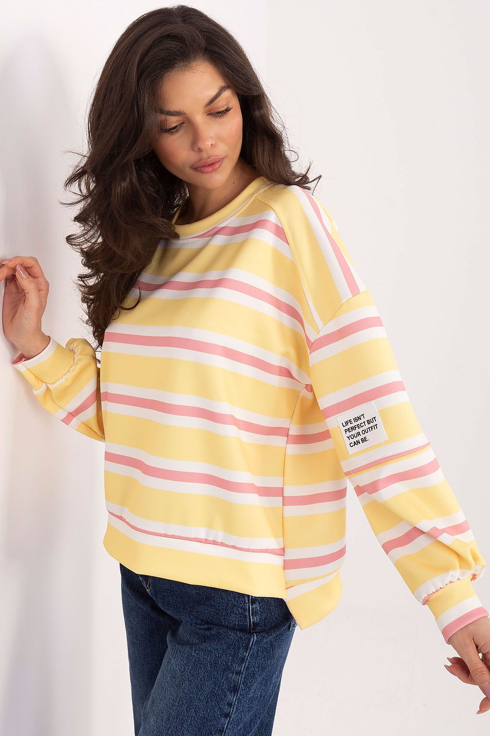 Woman wearing a yellow and pink striped sweater on a white background