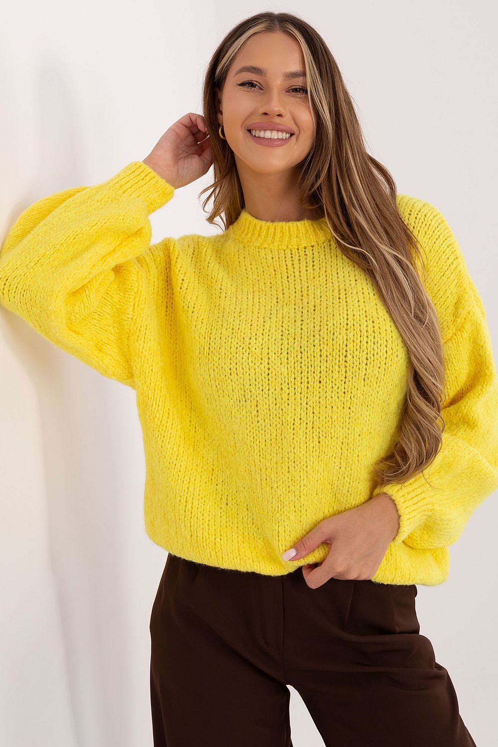 Woman wearing a bright yellow sweater against a white background