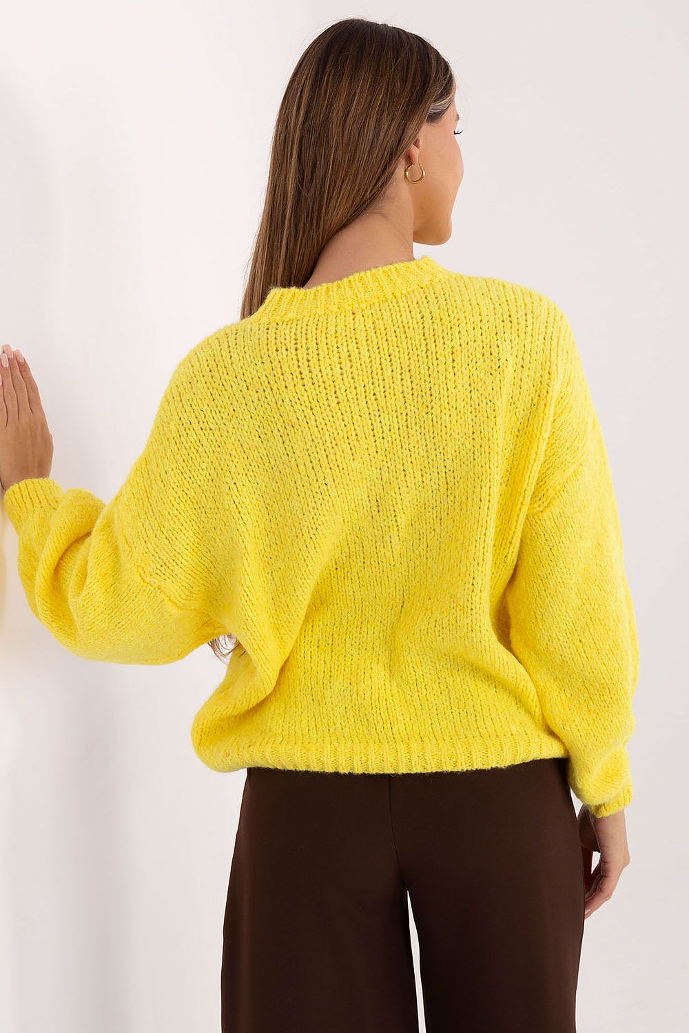 Person wearing a yellow sweater against a white background