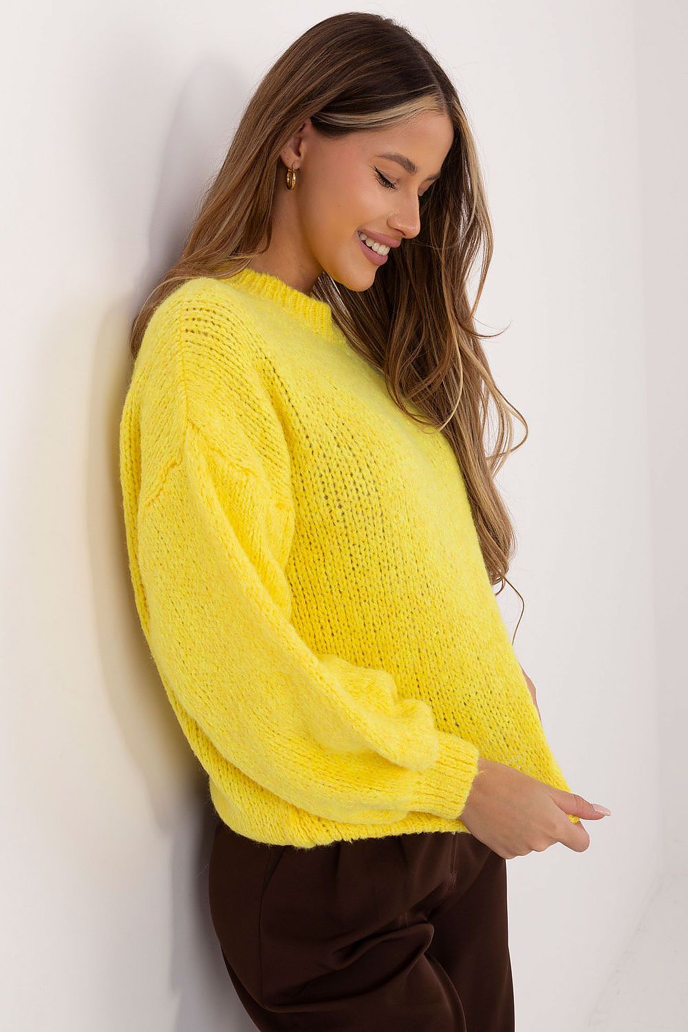 Woman wearing a bright yellow sweater against a white background
