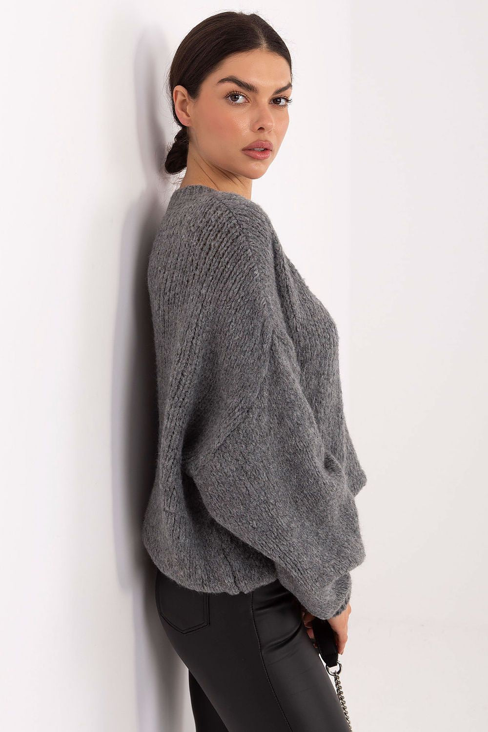 Woman wearing a gray sweater against a white background