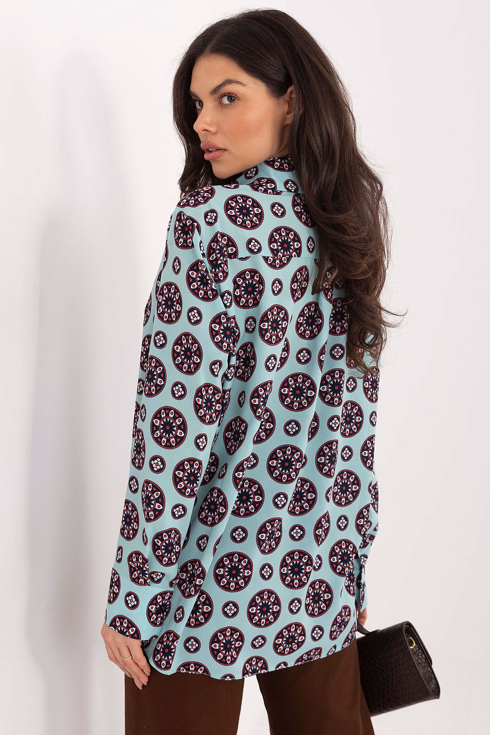 Woman wearing a patterned shirt with a plain background