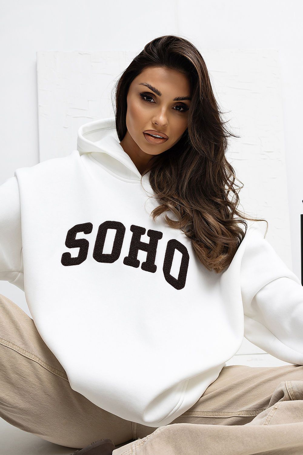 Woman wearing a white hoodie with 'SOHO' text on a white background