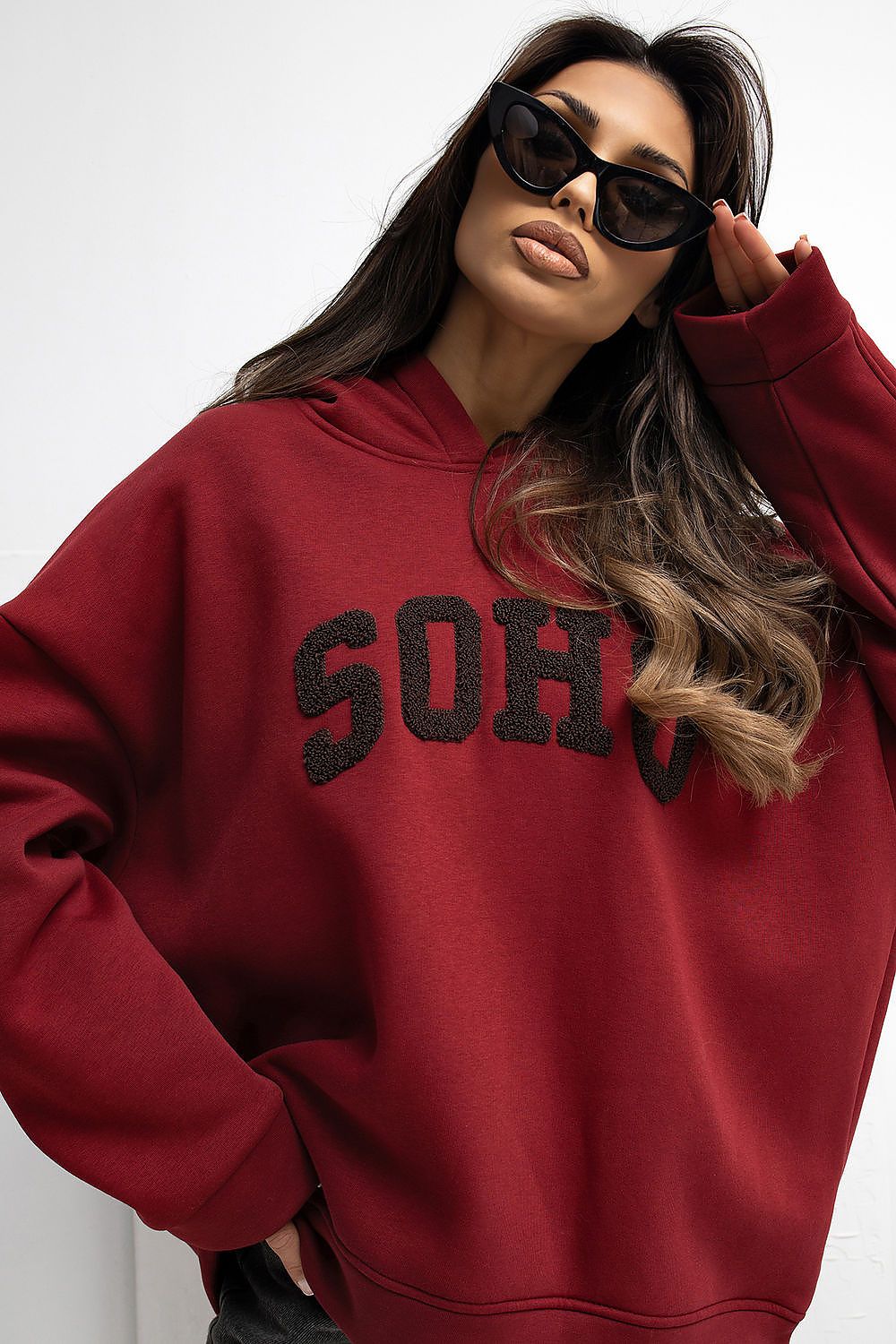 Person wearing a red hoodie with 'Soho' text and sunglasses on a white background