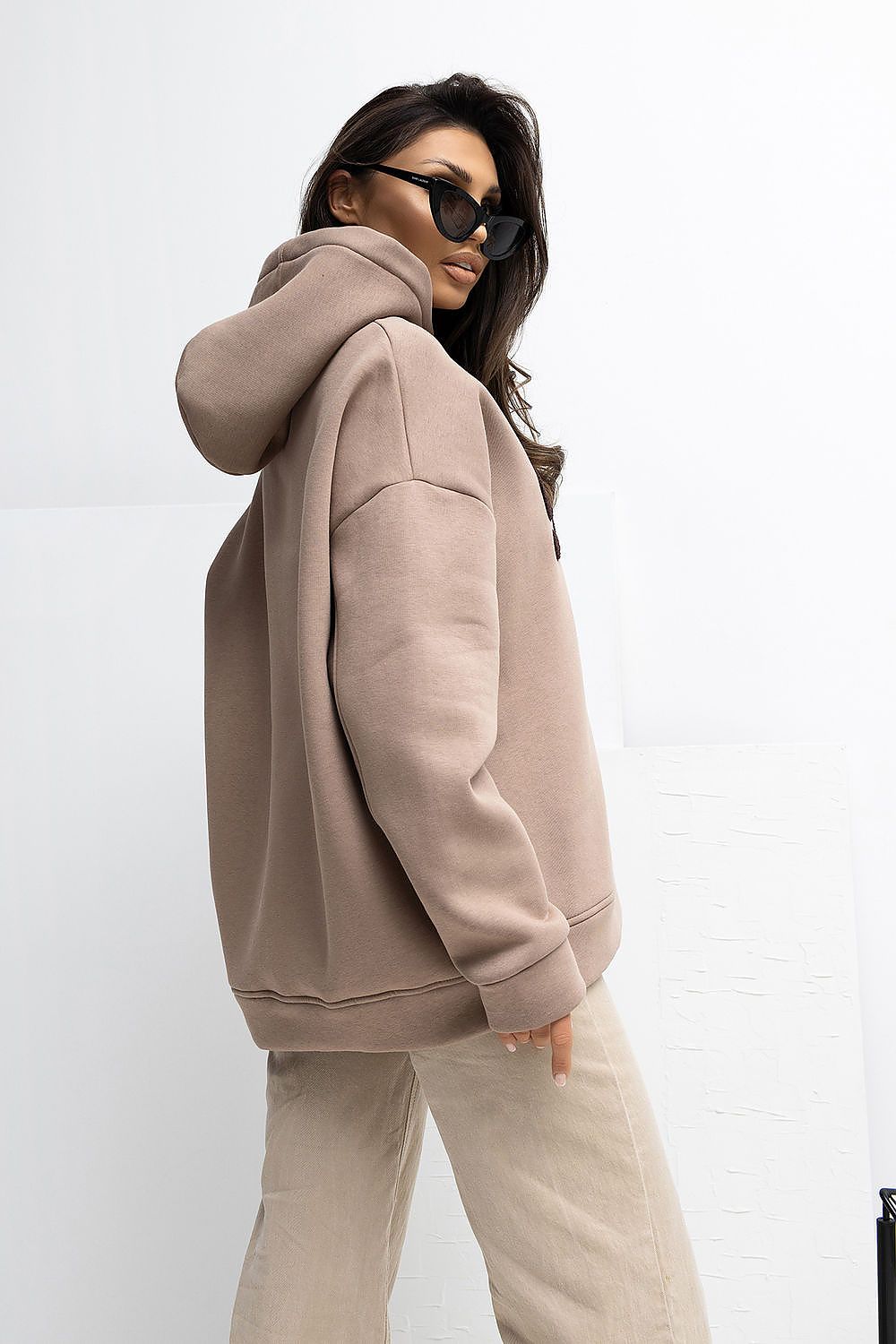 Person wearing a beige hoodie and pants on a white background