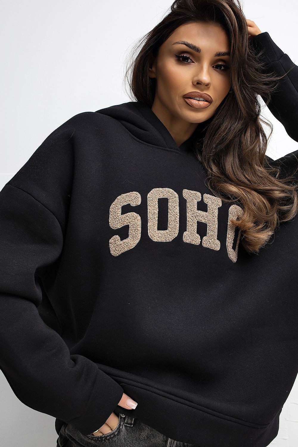 Woman wearing a black hoodie with 'SOHO' text on a white background