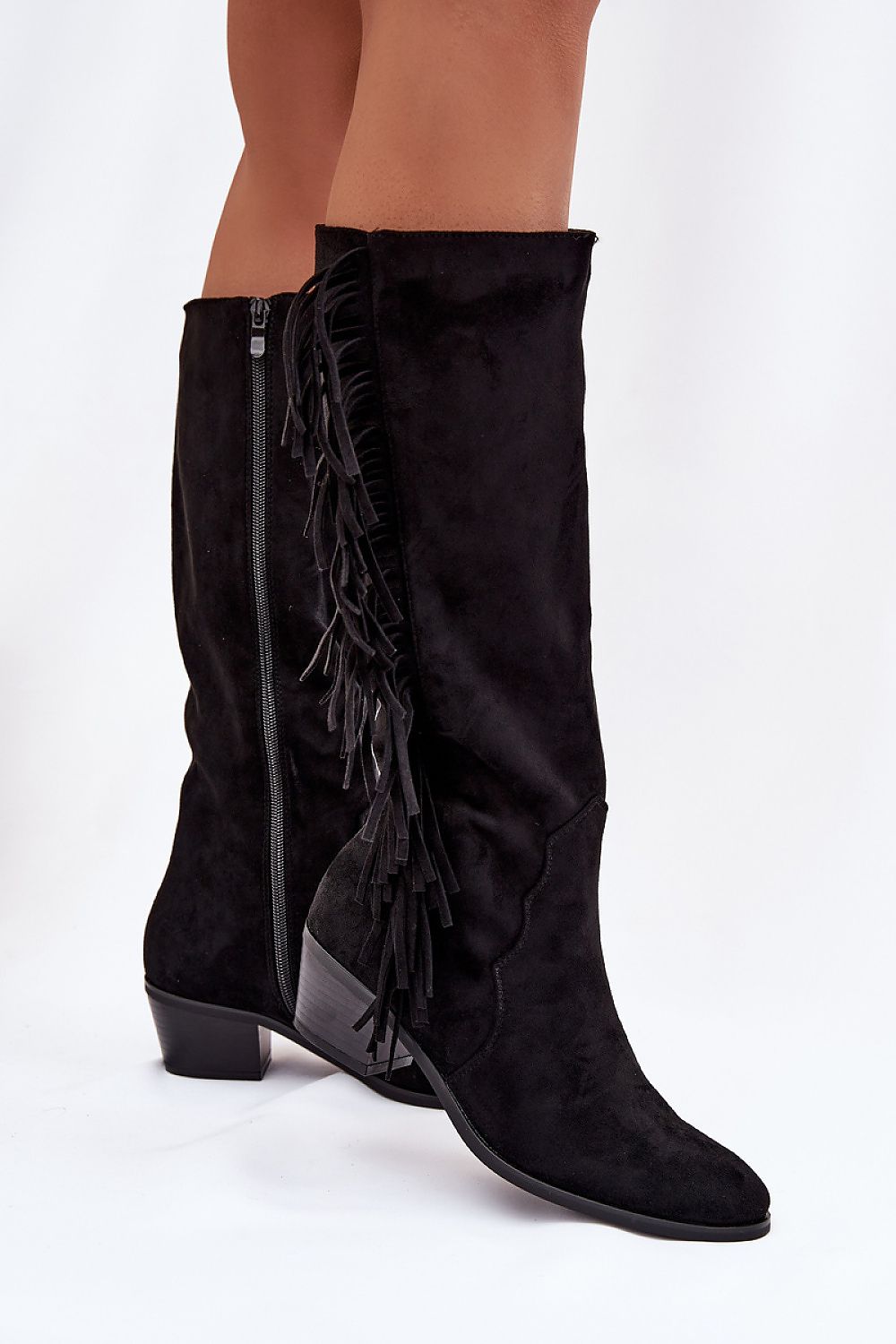 Black suede knee-high boots with fringes on a white background