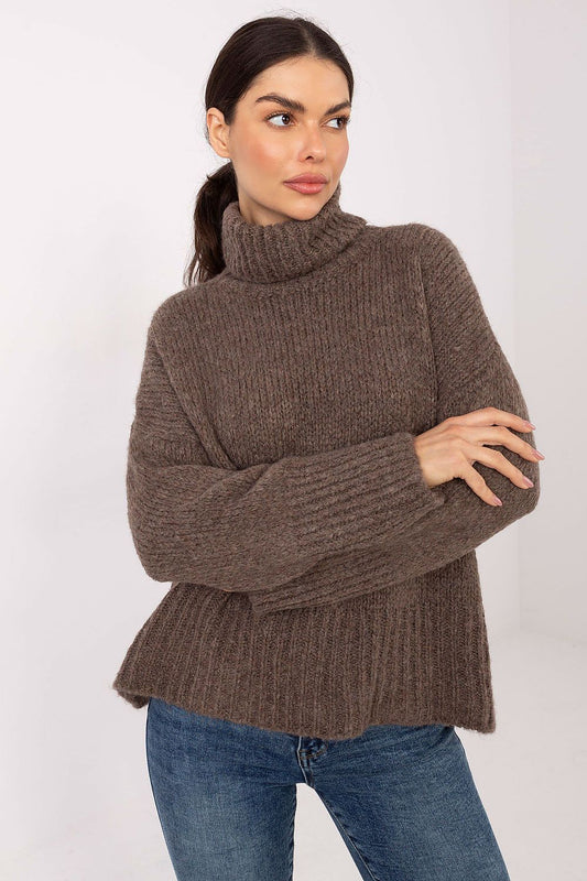 Woman wearing a brown knitted sweater and blue jeans on a white background
