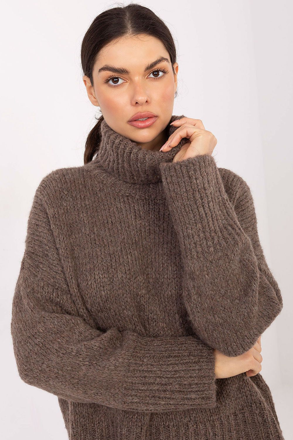 Woman wearing a brown knitted sweater against a white background