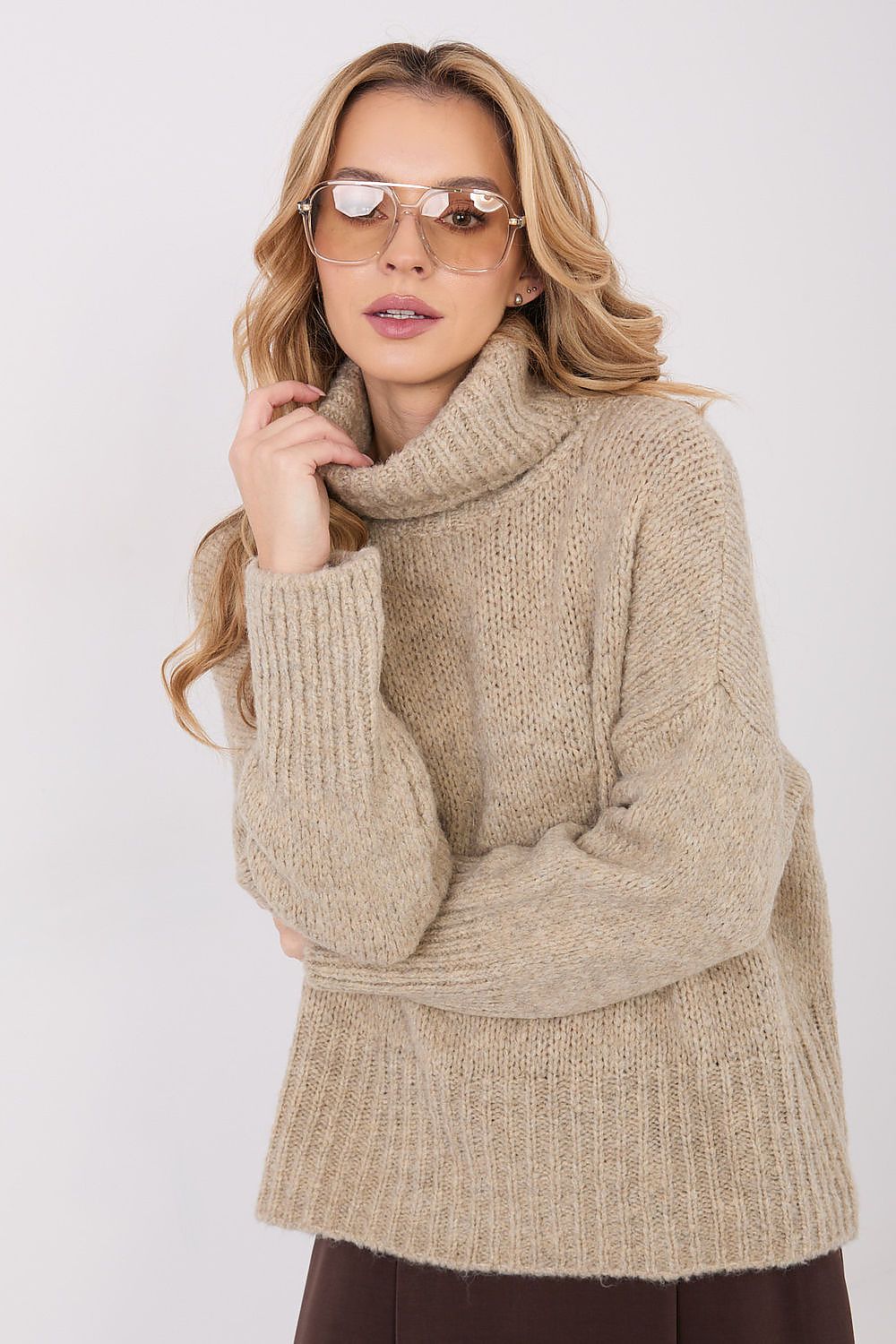 Woman wearing a beige knitted sweater and sunglasses on a white background
