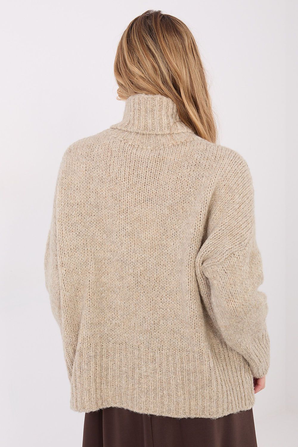 Person wearing a beige knitted sweater on a white background