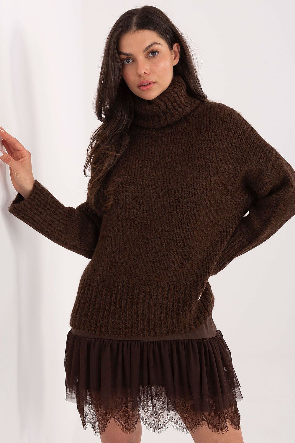 Woman wearing a brown knitted dress with a turtleneck and lace hem on a white background
