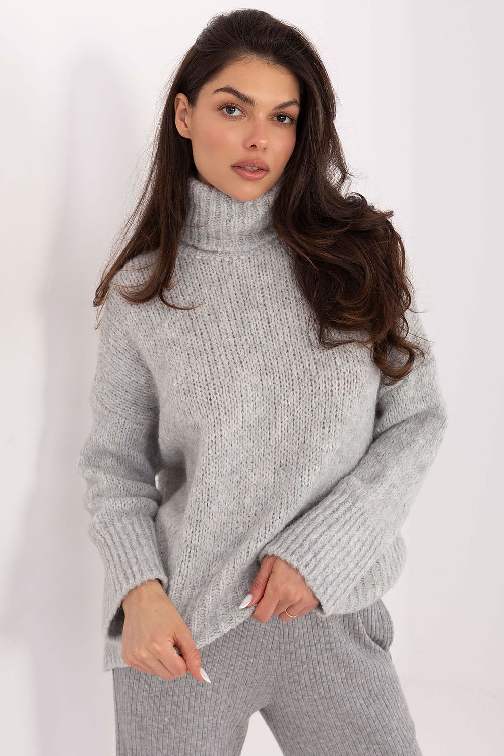 Woman wearing a gray knitted sweater and pants on a white background
