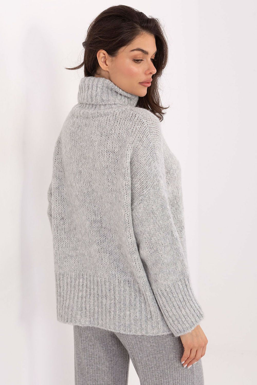 Woman wearing a gray knitted sweater on a white background