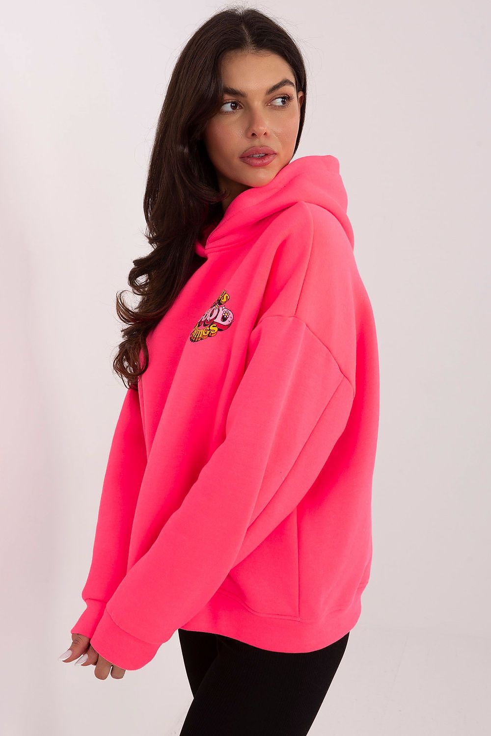 Woman wearing a bright pink hoodie with a small design on the chest against a plain background