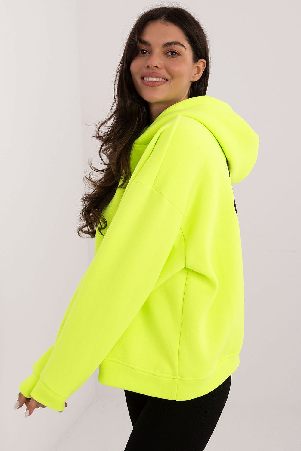 Woman wearing a bright yellow hoodie against a plain background