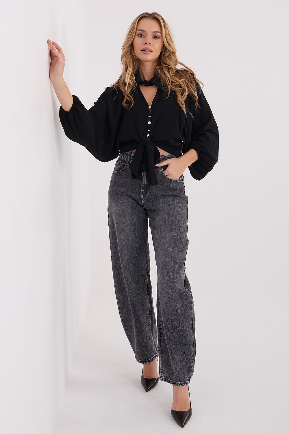 Front view of elegant classic puff-sleeve shirt with tie hem in black with jeans