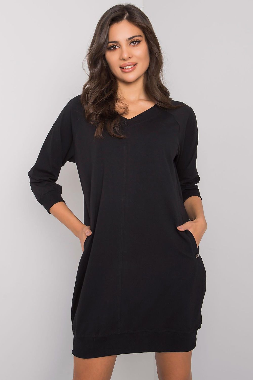 Woman wearing a black dress with long sleeves on a gray background