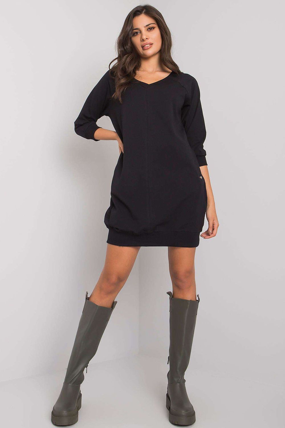 Woman wearing a black dress and gray boots on a white background